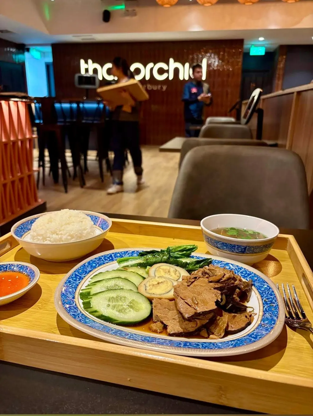 Stewed pork leg with rice, egg and broth on a bamboo tray